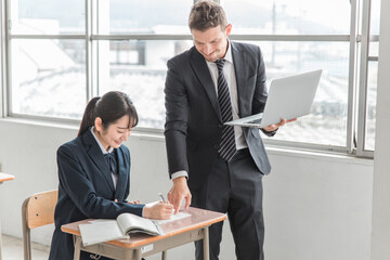 学校・塾でノートパソコンを使って勉強する高校生・中学生と外国人講師（ICT教育）
