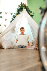 A little boy lying in a children's wigwam decorated for Christmas © fotofabrika