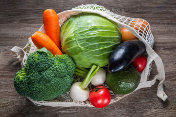 empty cotton wicker, eco friendly bag with fresh vegetables for shopping on wooden background, concept of healthy eating