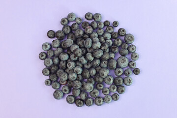 Blueberry a lot on purple background. Heap of berries. Cosmetics product advertising backdrop. Top view, flat lay.