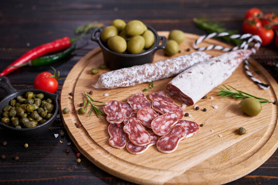 Traditional Spanish fuet salami sausage on wooden cutting board at domestic kitchen