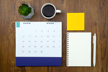 Calendar with note paper and coffee on wooden texture background. Plan notepad list concept....