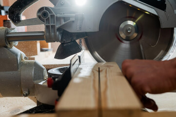 Master cuts the board with a circular saw in the workshop. 