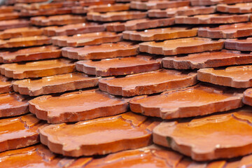 Orange clay tiles overlapping each other on the roof. Geometric pattern from old tile. Selective focus. Shallow DOF. Horizontal.