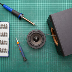 Audio speaker repair concept. Square photo. Workplace broken music speaker and repair tools. Top...