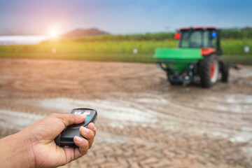 Hand to press remote control for  pushcart or tractor truck is rotary tillers for excavator in the farm for gardening with sunlight  at the plantation agriculture. Driverless tractor.