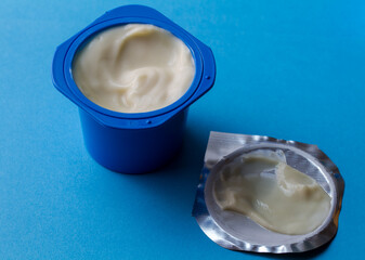 Blue yogurt pot on blue background - kid's  yoghurt in a cup with text space