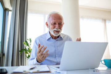 Portrait of handsome senior business coach having video call, talking to camera, explaining something. Webinar, video conferencing, online meeting concept