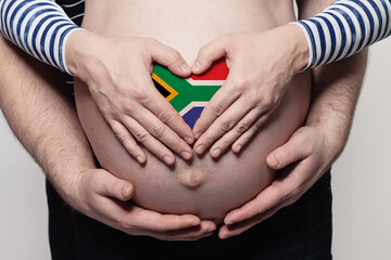 Man embracing pregnant woman belly and heart with flag of South African Republic colors closeup
