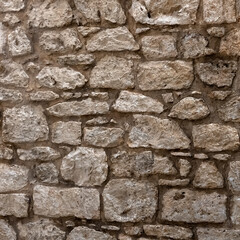 Background texture of newly repaired wall made with cream coloured stones and cement pointing