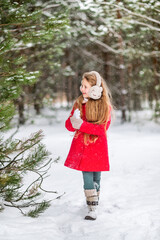 girl in a red coat walks in the winter forest