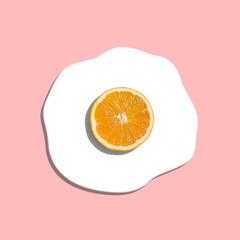 Orange slice instead of egg yolk forming fried egg on pastel pink background. Summer sunny side up egg minimal concept - 551752026