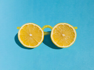 Yellow sunglasses made from fresh lemon slices and plastic lemonade straws on bright blue background. Summer minimal concept with sharp shadows. Funny idea - 551752047