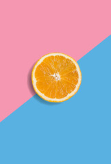 Minimalistic summer fruit tropical composition. Half of juicy fresh orange on light pastel pink and blue background. Citrus fruit refreshment. Vitamins, fresh healthy food concept. Copy space - 551752059