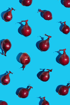 Red onion pattern on bright blue background. Top view flat lay composition. Minimal concept with harsh light and sharp shadow