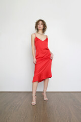 Woman in red silk satin camisole dress, studio shot.