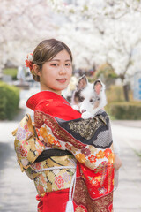 楽しそうに笑う赤い振袖を着た女性と白毛の犬