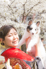 楽しそうに笑う赤い振袖を着た女性と白毛の犬