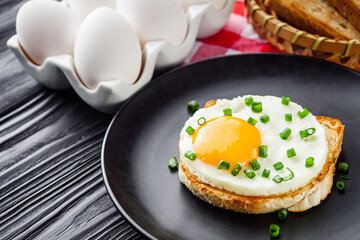 delicious fried egg sandwich on black rustic wooden background