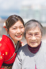 おばあちゃんと嬉しそうに写真を撮る赤い振袖を着た女性