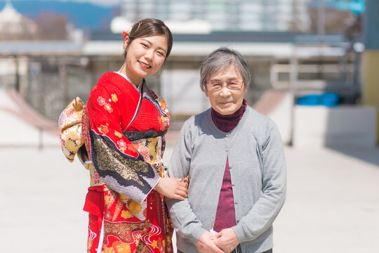 おばあちゃんと嬉しそうに写真を撮る赤い振袖を着た女性