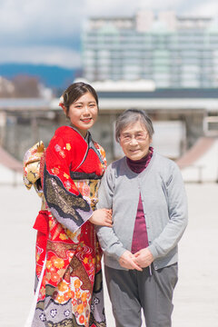 おばあちゃんと嬉しそうに写真を撮る赤い振袖を着た女性
