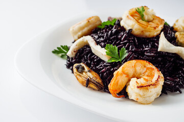 delicious black rice with shrimps and seafood on a white background