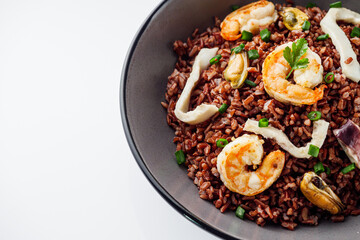 delicious red rice with shrimps and seafood on a white background