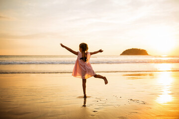 Fototapeta na wymiar Happy little caucasian girl five years old walking on the tropical beach on sunset