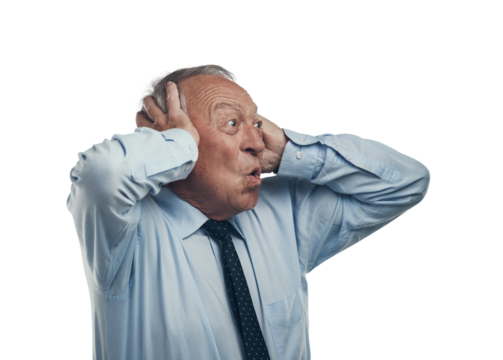 PNG shot of a senior businessman standing against a grey studio background with his head in his hands and looking shocked
