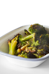 broccoli, oven roasted in olive oil,  in an enamel dish bowl. Isolated on a white background