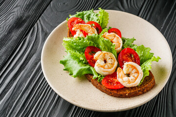 delicious Italian bruschetta with shrimps on a black wooden rustic background