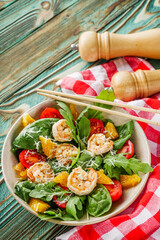 delicious fresh shrimp salad with orange and cherry tomatoes on a wooden rustic background
