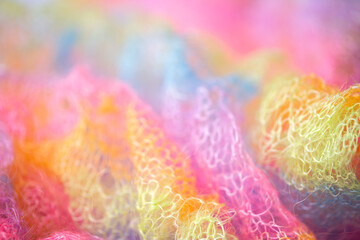 Knitted surface woolen items rainbow colored as a background. Closeup of soft multicolored knitted texture patterns. Warm winter clothes. Background textile surface with copy space for text. blurred