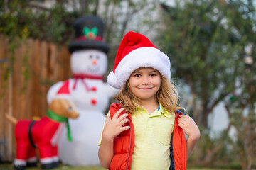 Happy New Year and merry Christmas. Kids portrait, outdoor. Child enjoying winter holiday in the front yard. House Christmas Decorated with Garlands.