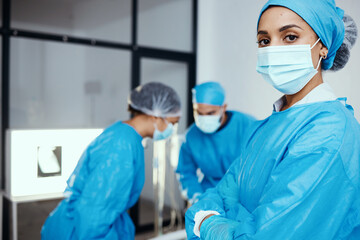 Medical, surgeon or doctor in scrubs and face mask in hospital with staff working during covid...