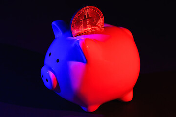 Piggy bank with Bitcoin on a dark background with red-blue backlight. Banking concept. Bitcoin mining concept