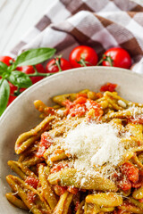 green cavatelli pasta with spinach in tomato sauce on a white wooden background
