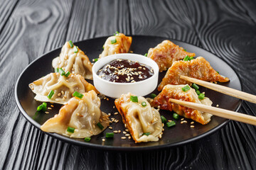 delicious fried gyoza dumplings on a black plate