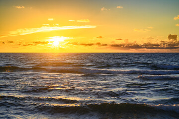 Sunset on tropical beach sea ocean with sunrise clouds. Banner for travel vacation. Scenery sky and reflection rays in water. Dusk, twilight on sea. Tranquil, golden sky background.