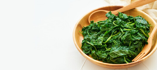 close up green cook leaf spinach salad in wood bowl on white table background. leaves spinach or...