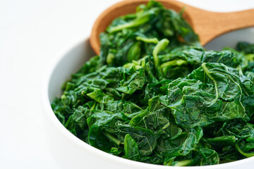 close up green cook leaf spinach salad in white bowl on white table background. leaves spinach or heap of spinach food salad                                                                      