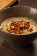 white beans soup with leek top with chopped bacon and hazelnuts