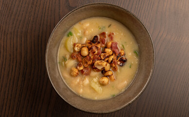 white beans soup with leek top with chopped bacon and hazelnuts