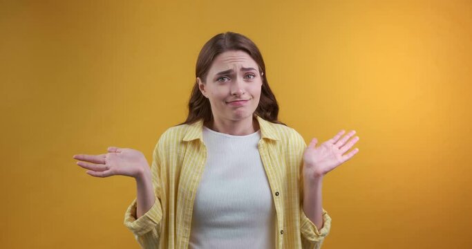 Confused beautiful young woman on yellow background