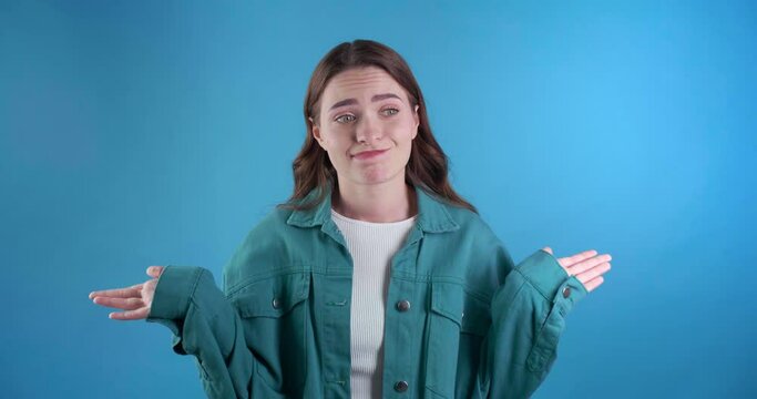 Confused beautiful young woman on light blue background