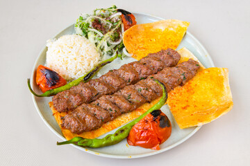 Grilled Turkish Adana, Urfa  Kebab with grilled vegetables, onion and rice on plate. Adana durum.