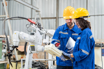 A team of male and female engineers meeting to inspect computer-controlled steel welding robots....