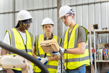A team of male and female engineers meeting to inspect computer-controlled steel welding robots. Plan for rehearsals and installation for use.