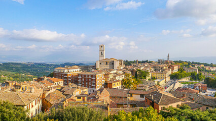 Obraz premium View of the city from above: you can see the towers, rooftops, and mountains. You can see the treetops in the foreground.